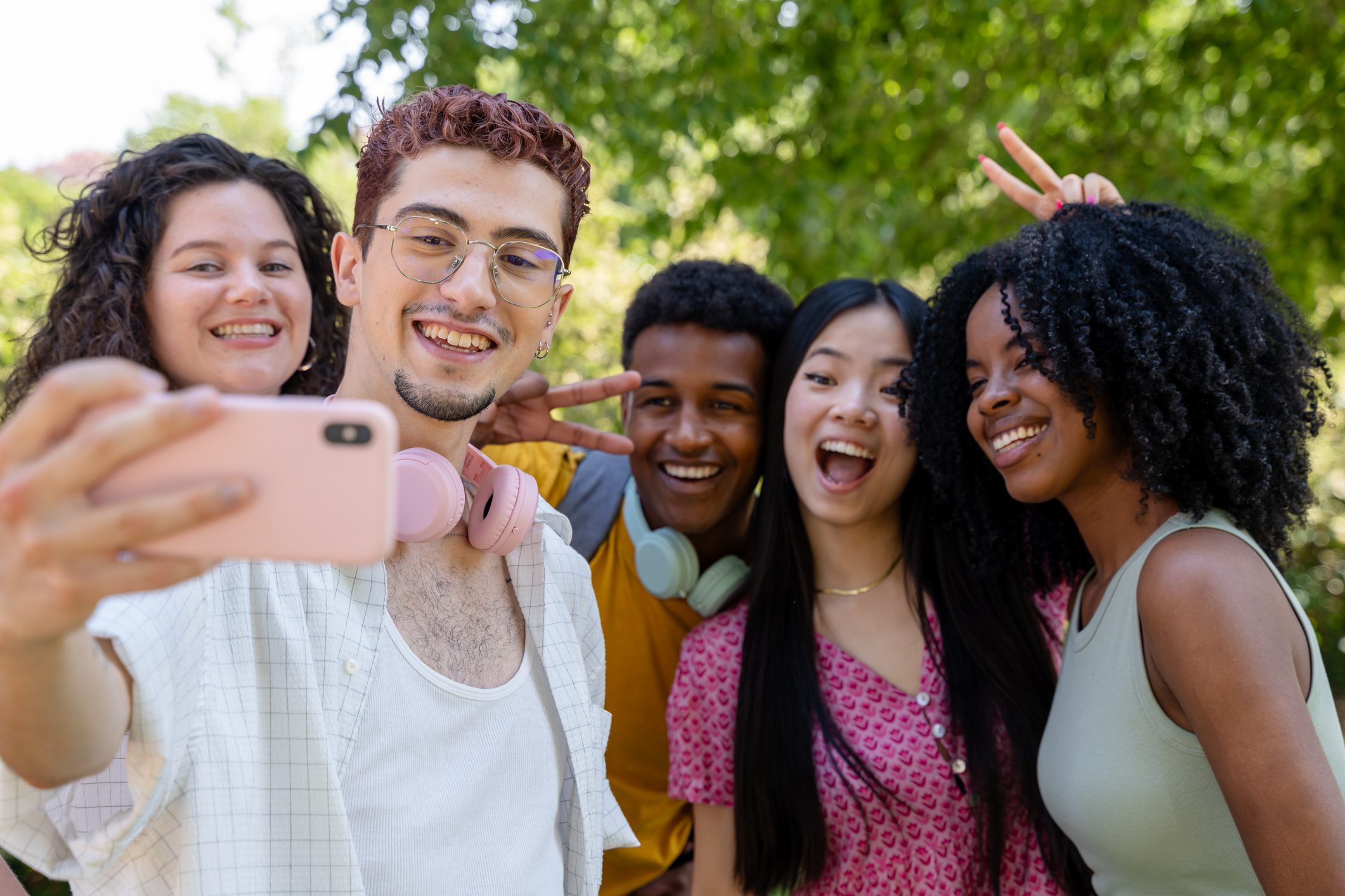 Young, enthusiastic friends capture a joyful moment with a group selfie in the park