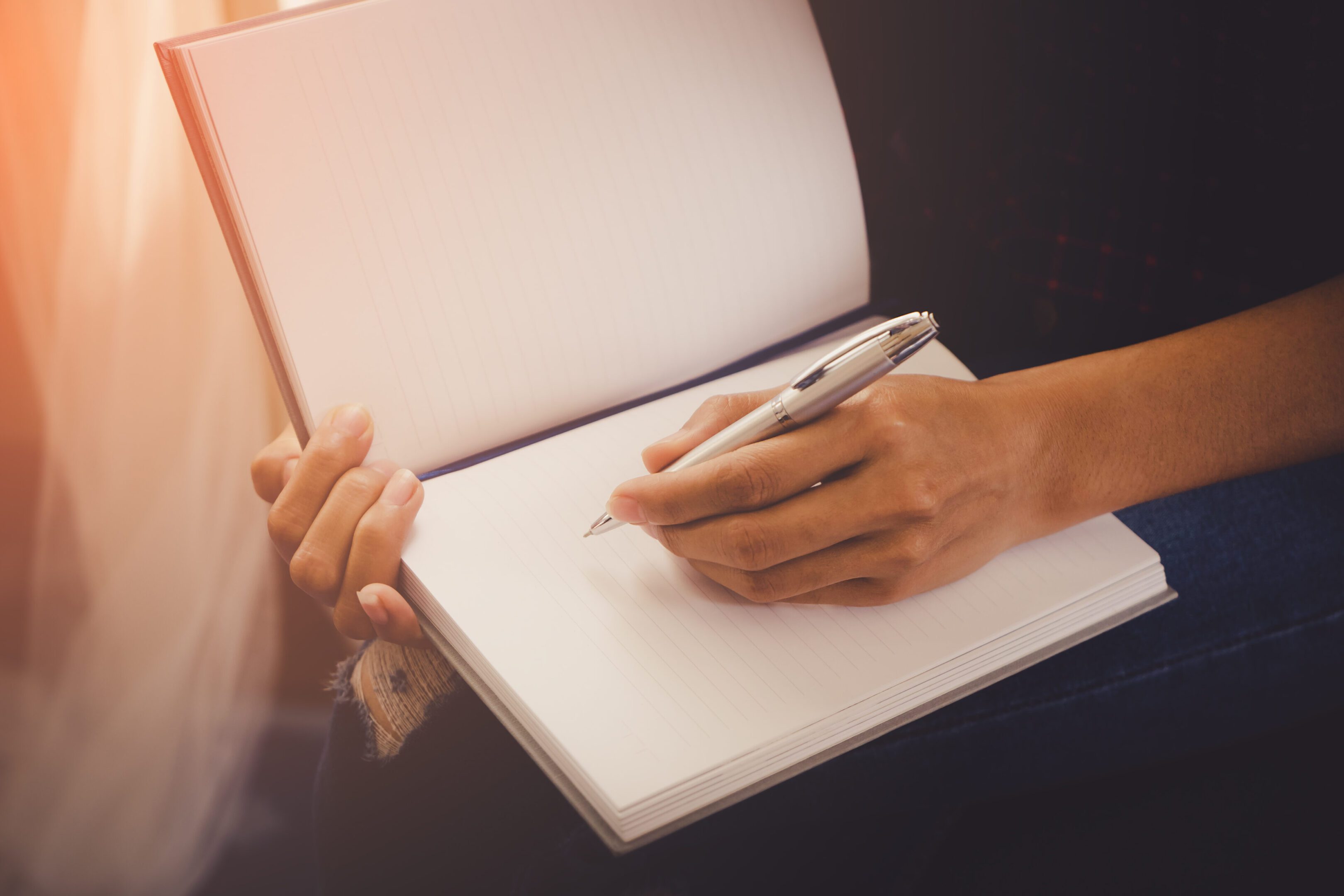 Female casual creative designer worker is writing note on notebook